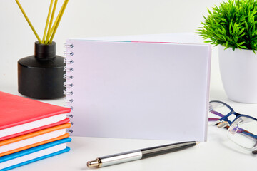 A clean notebook with a place to write on a white background next to business supplies