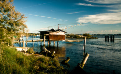 Tranquil waters embrace a picturesque scene of fishing boats and rustic huts along the shores of...