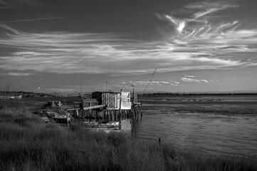 Tranquil waters embrace a picturesque scene of fishing boats and rustic huts along the shores of...