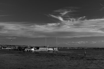 Tranquil waters embrace a picturesque scene of fishing boats and rustic huts along the shores of...