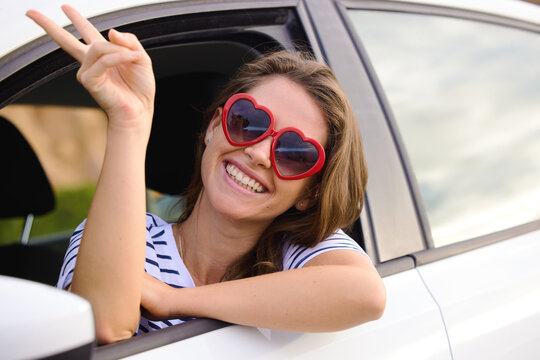 Happy woman, peace sign and portrait in car for travel, adventure or road trip in city for summer vacation. Person, smile and heart glasses with gesture for emoji, comic and crazy in transportation