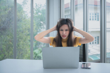Asian businesswomen Feeling stressed While he looks at unsuccessful earning from a computer notebook, at workplace, to people and business loss concept.