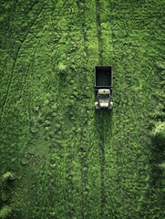 Blue tractor mowing green field, aerial view