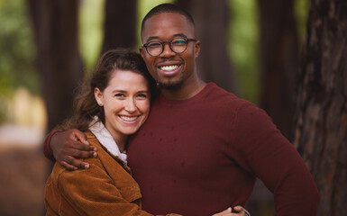 Love, portrait and couple hug in outdoor for camping in wilderness on anniversary date in Norway, countryside. Interracial people, travel and holiday or vacation in forest for peace and adventure.
