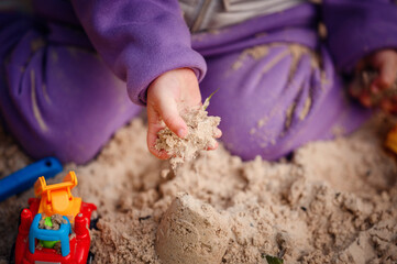 A close view of a toddler's hands playing in the sand, capturing the essence of tactile learning...
