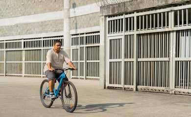 hombre latino al aire libre usando su bicicleta muy tranquilo por el parque  - obrazy, fototapety, plakaty