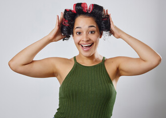Hair, portrait and excited woman in studio with roller, beauty or natural curly styling on grey...