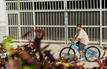 hombre latino de mediana edad montando bicicleta por el parque al aire libre 