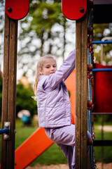 A focused young girl climbs on a playground, her gaze fixed on the next step, symbolizing...