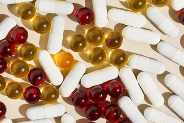 Close-up of transparent pill capsules of yellow, red and white colors on a beige background. Treatment of diseases, depression, antibiotics, vitamins. Image for your design