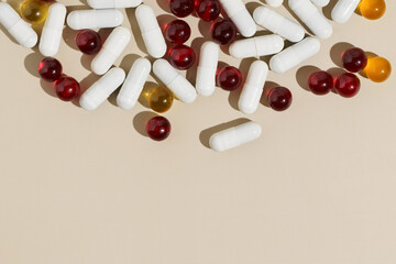 Top view of red, yellow and white capsule pills on beige isolated background. Place for your...
