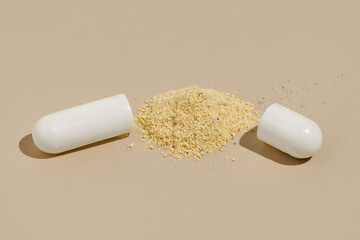 Close-up of half capsule and powder component on beige isolated background. Concept of scientific medicine, facts about pills, health.