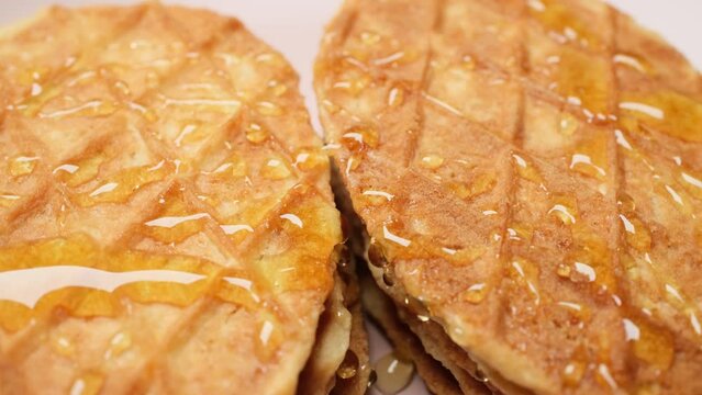 Close-up Belgium Crispy Butter Waffles pouring honey on 360 degree rotating plate