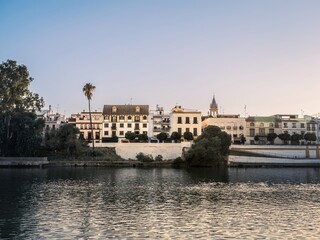 Naklejka premium Colorful buildings including homes and shops face the Guadalquivir River in the Triana District of the Analusian city of Seville, Spain.
