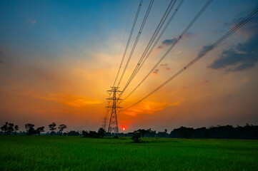 Silhouette street light post, electric pole and high voltage tower.High voltage transmission pole against evening sunset sun background.