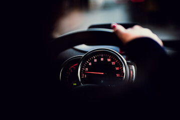 Speedometer instrument cluster visible behind a hand on a steering wheel