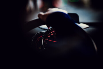 Speedometer instrument cluster visible behind a hand on a steering wheel