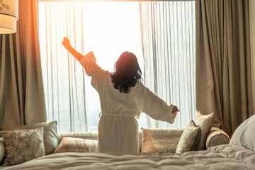 Hotel relaxation on lazy day with Asian woman waking up from good sleep on bed in weekend morning...