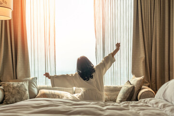 Hotel relaxation on lazy day with Asian woman waking up from good sleep on bed in weekend morning...