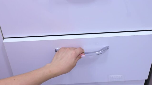 Woman hand closing an empty drawer of white cabinet pulling by the handle