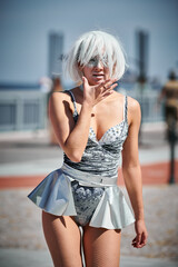 Young sexy girl in space silver micro skirt dancing with smooth, feminine and graceful movements, female outdoor dance performance on seaside promenade creating an arousing outdoor spectacle