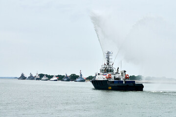 Fireboat sailing along Russian naval forces parade warships with military helicopters along...