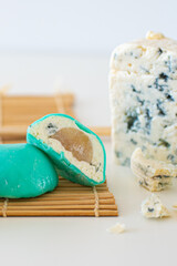 Mochi green color on bamboo makisu with blue cheese on light background. Japanese traditional frozen delicious dessert mochi. ice cream with dough of sticky rice. Asian cuisine.