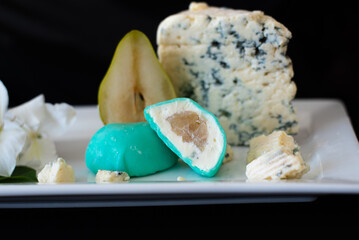 Mochi green color on white plate with pear and blue cheese on black background. Japanese traditional frozen delicious dessert mochi. ice cream with dough of sticky rice. Asian cuisine.
