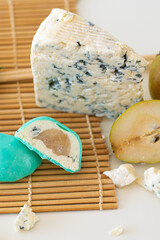 Mochi green color on bamboo makisu with pear and blue cheese on light background. Japanese traditional frozen delicious dessert mochi. ice cream with dough of sticky rice. Asian cuisine.