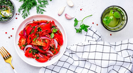 Fresh juicy summer tomato salad with parsley garlic and olive oil dressing and red onion, white table background, top view - 790155949