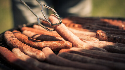 close up of a hand holding a sausage in a barbecue