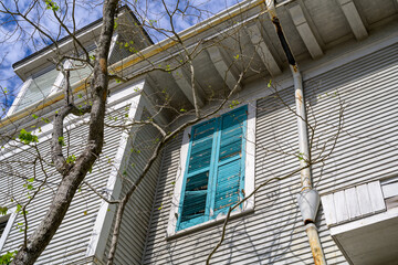 Side of old wooden home in New Orleans that needs a paint job and shutter repair