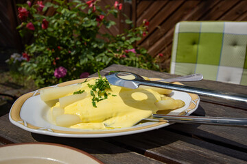 Fresh white asparagus on a plate with sauce hollandaise and asparagus tongs.