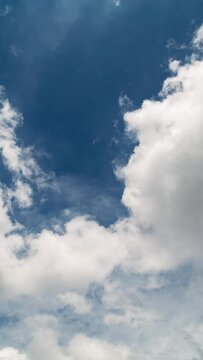 Vertical video - Timelapse of white puffy clouds rolling under blue sky