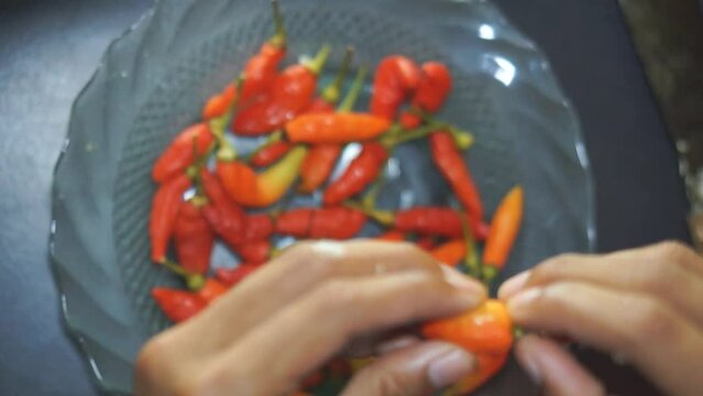 a man is cleaning red cayenne peppers by hand