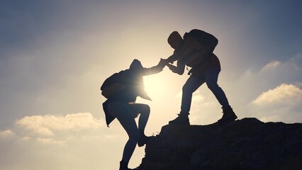 business. teamwork helps hand down business silhouette concept. a group of tourists lend a helping hand, climbing rocks, mountains, lend a helping hand. teamwork people climbers climb to top travel