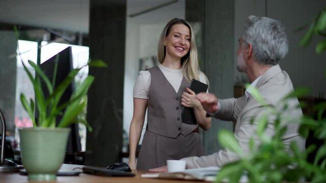 Manager talking with his employee in modern office. Company director is happy, satisfied for workers quality work.