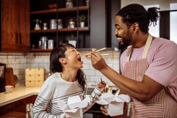Multiracial couple eating sushi together at home. - 790197346