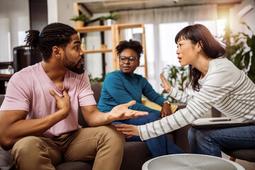 Arguing African American couple consulting mental health problem with Asian psychologist,...