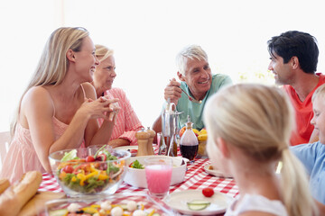 Happy, family and young girl in living room at table with salad, vegetables and eating together for lunch. Mom, dad and children on vacation at childhood house visiting grandparents for memory