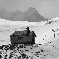 Schwarzweiss Aufnahme einer kleinen Kapelle auf einem Hügel im Winter, mit schneebedeckten...