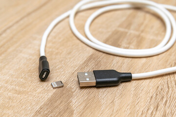 Damaged broken micro iPhone Lightning input USB port charger cable,torn mobile phone charging wire on wooden surface.
