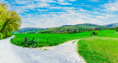 landscape with trees and blue sky. Odenwald panorama. Cycling season. green meadow with a bicycle. Beautiful spring landscape with hills in the background. Germany