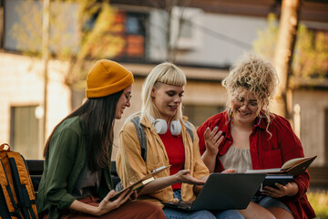 Female students working together digitally while seated outdoors