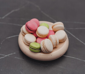 A plate of sweet macaroons on a dark table in the kitchen.