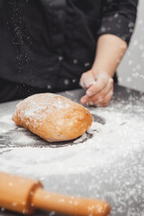 An experienced chef cooks in a professional kitchen prepares dough with flour for making ciabatta bread.