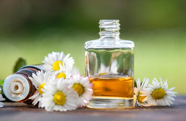 bottles of essential oil and daisies with fresh mint leaf on a wooden table  outdoors - 790213358