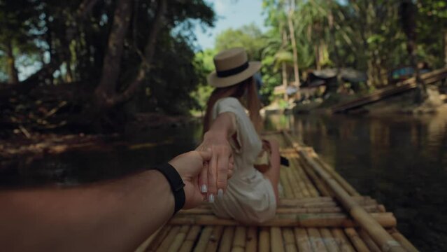 Female tourist floats on bamboo raft. Woman tourist enjoying the bamboo rafting on the river with man beautiful nature landscape on smartphone. Vacation, tropical jungle travel, follow me concept.