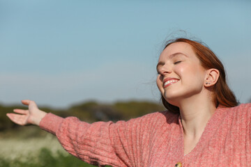 Girl sunbathes in the spring sun with her eyes closed and arms outstretched