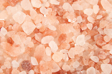 Pink salt rocks or Himalayan salt texture. Top view of many coarse salt rocks in different orange to white tones. Used to flavor food, presentation and cooking. Selective focus.